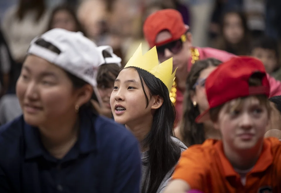 students sitting down wearing crowns and hats
