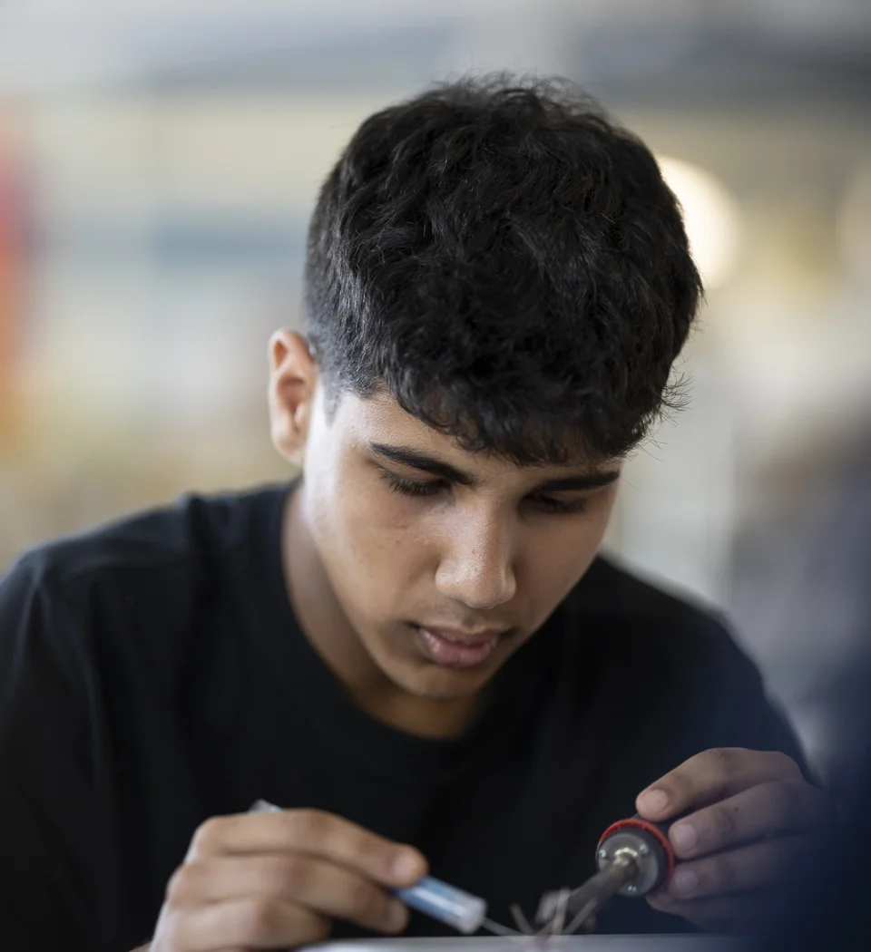 male student using saudering tools