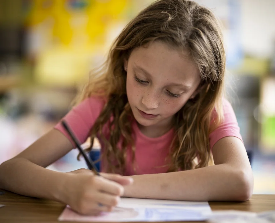 student drawing on paper at a table