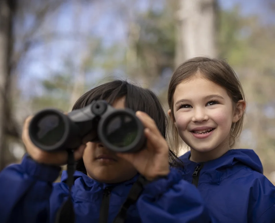 2 students outside using binoculars