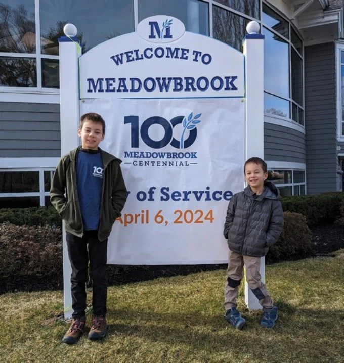 2 students standing in front of Meadowbrook Day of Service 2024 sign