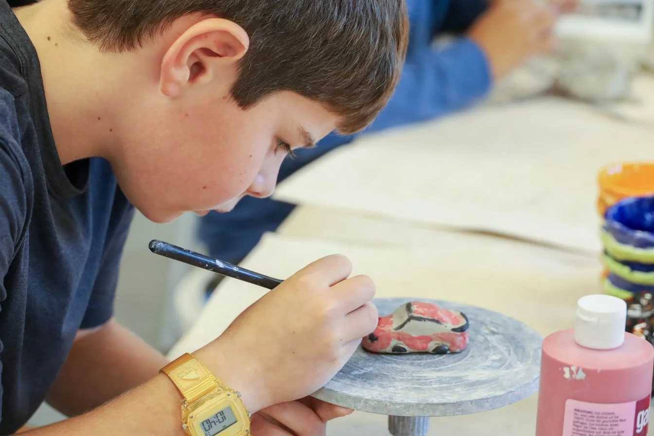 student painting a clay car