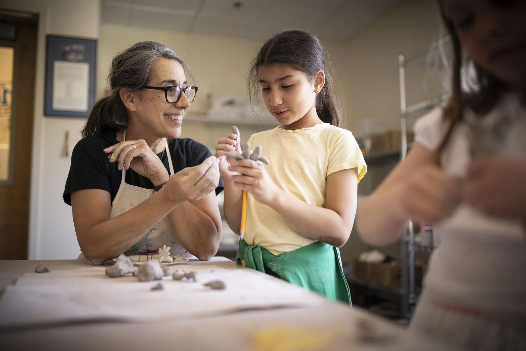 student and teacher shaping clay